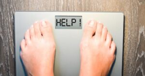 Das Geheimnis der Nährwerttabelle – Teil 5: Das richtige Wissen zum Abnehmen nutzen Person steht auf Waage